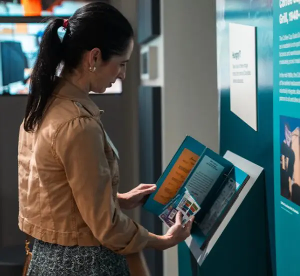 Woman reading a brochure while standing inside the Levine Museum of the New South, surrounded by exhibits