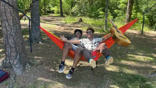 An image of two people in a hammock at a team picnic for the POC Youth Advisory Group.