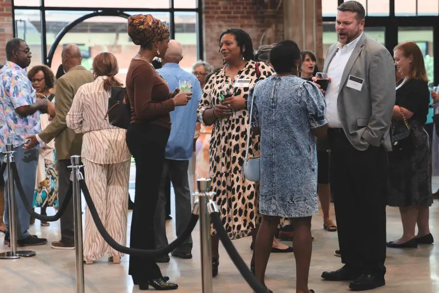 Group of people conversing inside the Levine Museum of the New South, surrounded by exhibits and displays